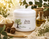 Pot de beurre de karité pur 50 g de La Savonnerie Blanchou présenté dans un décor naturel avec noix de karité, huile végétale et feuillage, idéal pour hydrater et nourrir la peau.