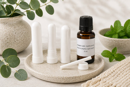 Inhalateur nasal aux huiles essentielles de menthe poivrée, eucalyptus radié, camphre et sapin baumier de La Savonnerie Blanchou, présenté avec son flacon d'huiles essentielles dans un décor naturel.