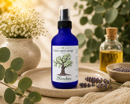 Lotion après-rasage naturelle fabriquée au Québec par La Savonnerie Blanchou, présentée dans une bouteille en verre bleu avec vaporisateur, entourée de lavande et d'huiles végétales dans un décor inspiré des soins corporels naturels.