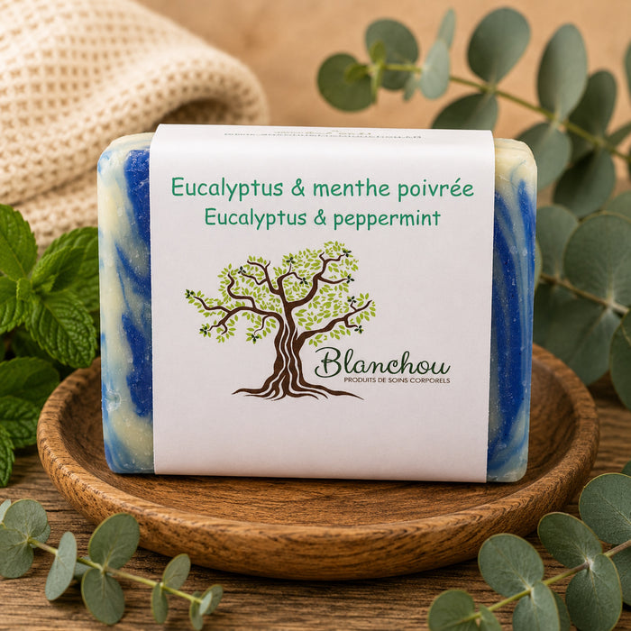 Savon artisanal eucalyptus et menthe poivrée La Savonnerie Blanchou présenté sur plateau de bois avec feuilles d’eucalyptus et menthe