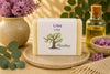 Savon artisanal lilas de La Savonnerie Blanchou présenté dans une ambiance naturelle avec fleurs de lilas et huiles végétales