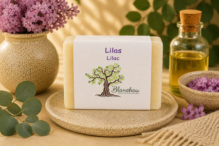 Savon artisanal lilas de La Savonnerie Blanchou présenté dans une ambiance naturelle avec fleurs de lilas et huiles végétales