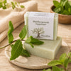 Savon artisanal à la menthe poivrée de La Savonnerie Blanchou présenté avec feuilles de menthe fraîche dans une ambiance naturelle apaisante