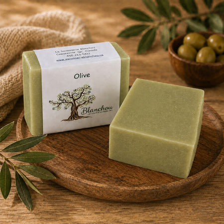 Savon artisanal à l’huile d’olive de La Savonnerie Blanchou présenté avec olives et feuillage dans une ambiance naturelle chaleureuse