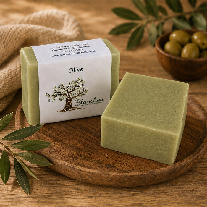 Savon artisanal à l’huile d’olive de La Savonnerie Blanchou présenté avec olives et feuillage dans une ambiance naturelle chaleureuse